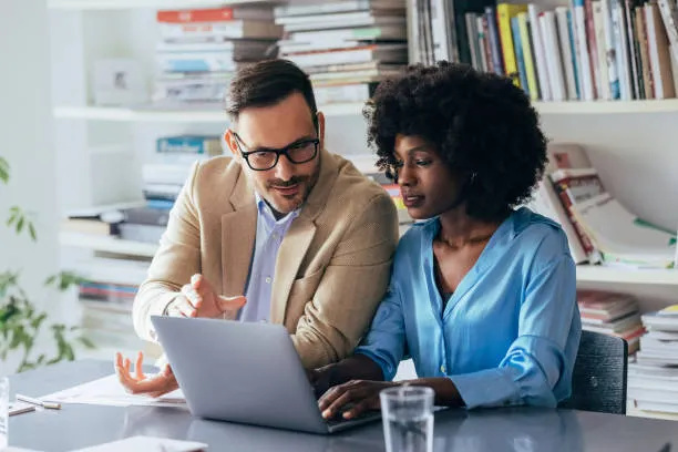 A mentor helping someone at a laptop