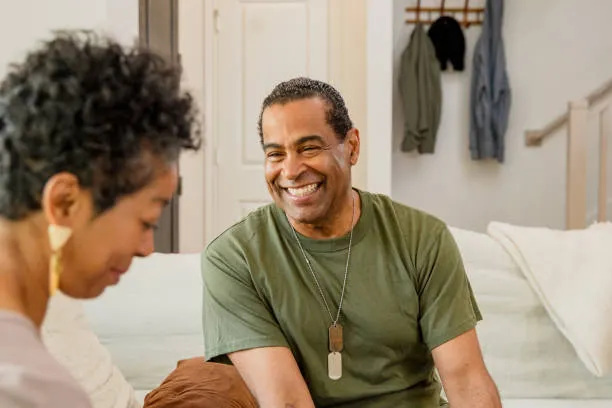 A smiling veteran talking with a friend at home